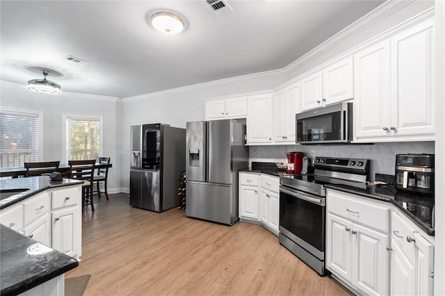 kitchen with white cabinets, light hardwood / wood-style flooring, decorative backsplash, ornamental molding, and stainless steel appliances