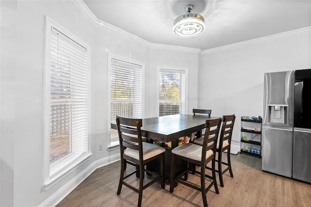 dining space featuring crown molding and light hardwood / wood-style flooring