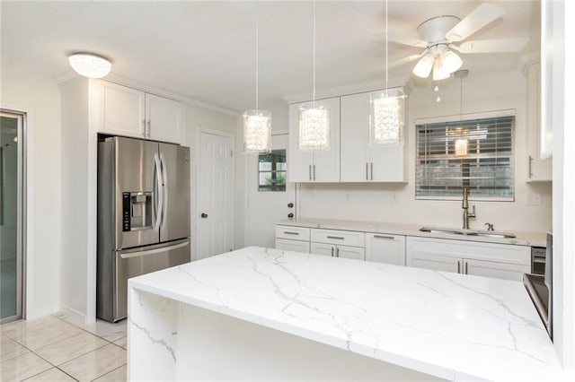 kitchen with light stone countertops, hanging light fixtures, stainless steel refrigerator with ice dispenser, sink, and white cabinets