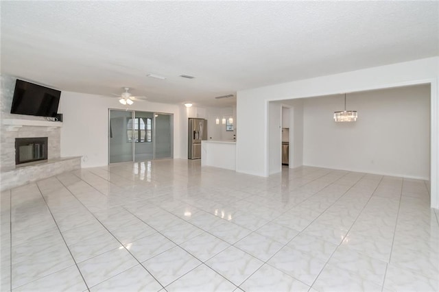 unfurnished living room with ceiling fan with notable chandelier and a textured ceiling