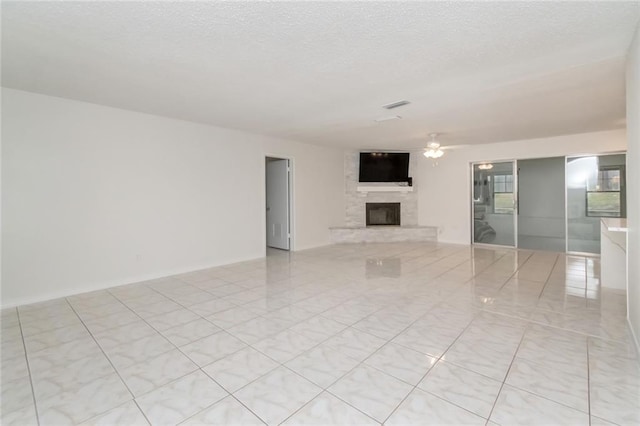 unfurnished living room with ceiling fan, a textured ceiling, and a large fireplace