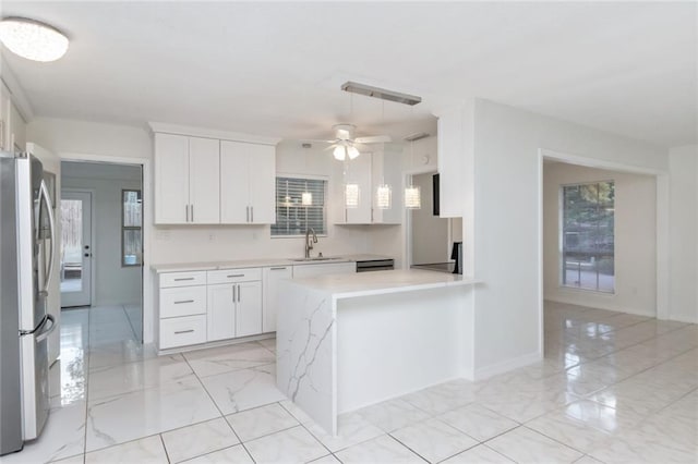 kitchen with white cabinetry, kitchen peninsula, ceiling fan, and stainless steel fridge