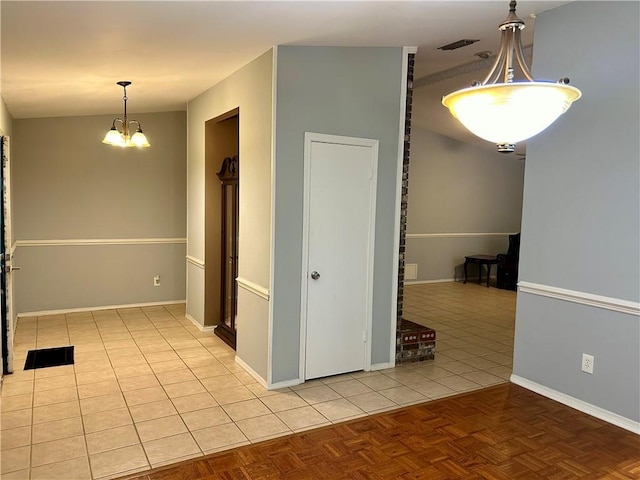 empty room with light tile patterned flooring and an inviting chandelier