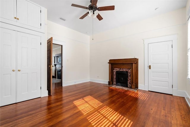 unfurnished living room with ceiling fan, dark hardwood / wood-style flooring, and a tiled fireplace