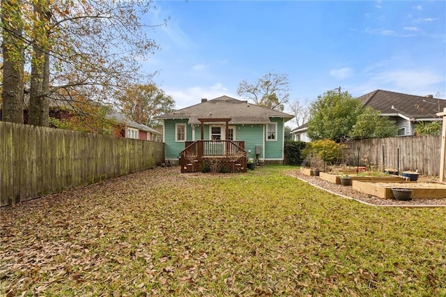 rear view of property featuring a wooden deck and a lawn