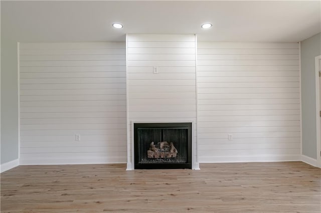 interior details with a fireplace, hardwood / wood-style floors, and wooden walls