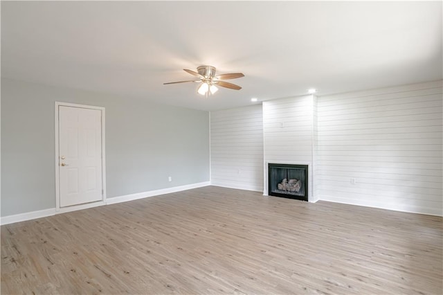 unfurnished living room featuring ceiling fan, a fireplace, and light hardwood / wood-style flooring