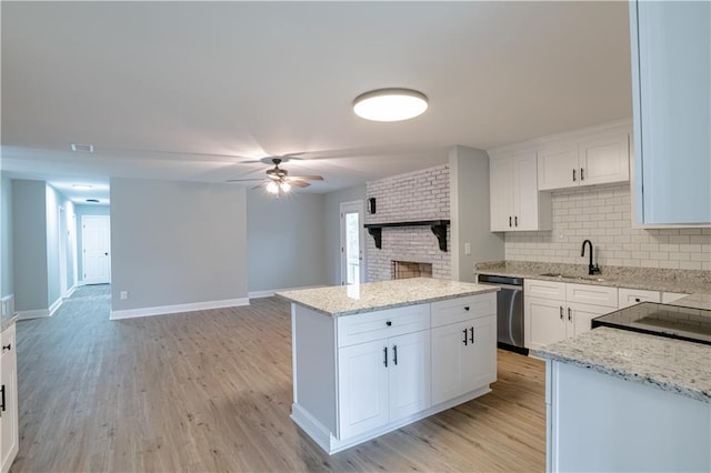 kitchen with white cabinets, stainless steel dishwasher, a kitchen island, and sink