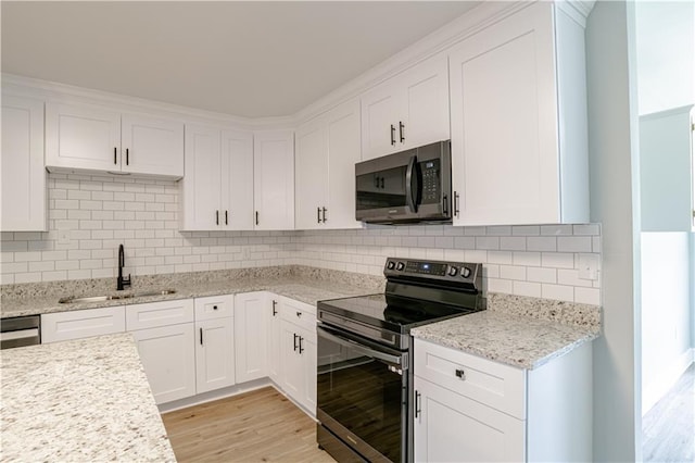 kitchen with sink, appliances with stainless steel finishes, decorative backsplash, white cabinets, and light wood-type flooring