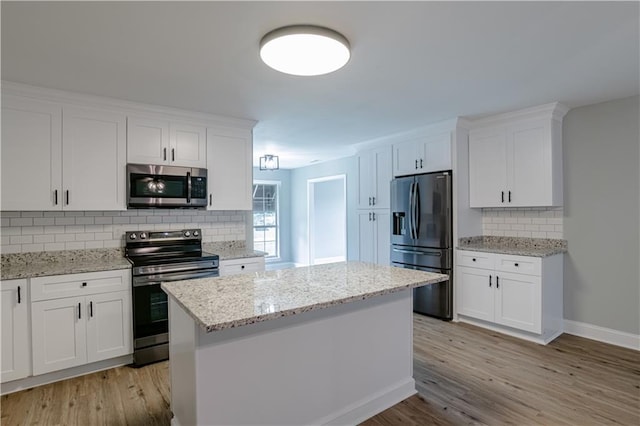 kitchen featuring stainless steel appliances, white cabinetry, a kitchen island, and light hardwood / wood-style flooring