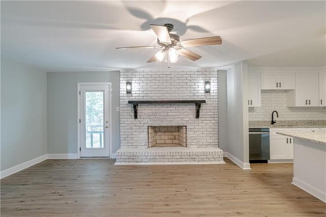 unfurnished living room featuring a fireplace, sink, and light hardwood / wood-style flooring