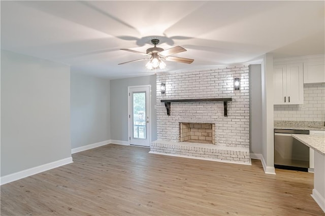 unfurnished living room featuring light hardwood / wood-style floors, a brick fireplace, and ceiling fan