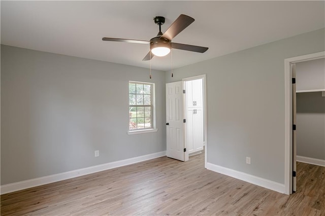 unfurnished bedroom with ceiling fan, light hardwood / wood-style floors, and a spacious closet