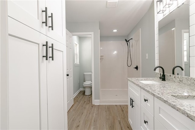 bathroom featuring a shower, vanity, hardwood / wood-style flooring, and toilet