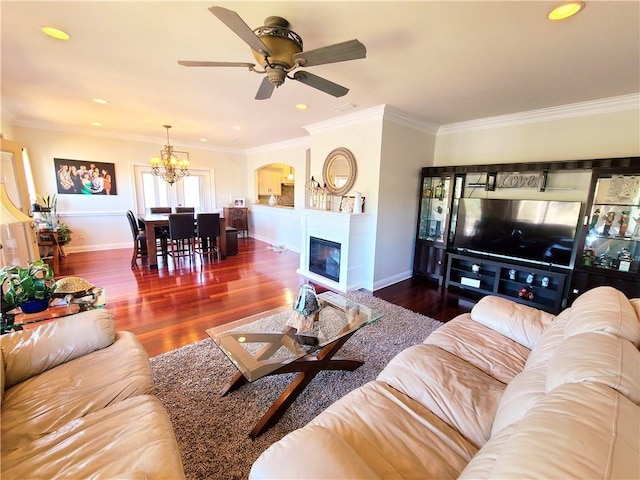 living room with crown molding, dark wood-type flooring, and ceiling fan with notable chandelier