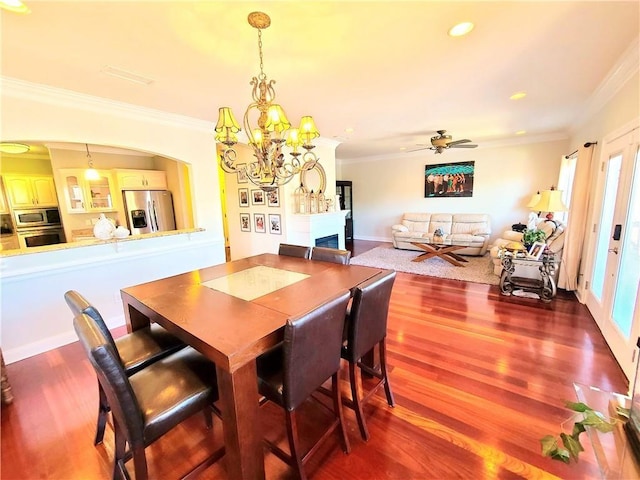 dining space featuring ceiling fan with notable chandelier, wood-type flooring, and crown molding