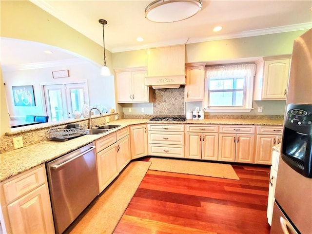 kitchen with decorative backsplash, appliances with stainless steel finishes, custom range hood, sink, and decorative light fixtures