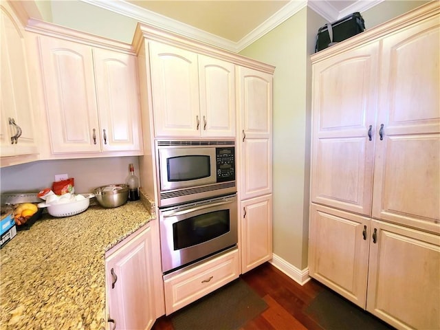 kitchen with dark wood-type flooring, light stone counters, crown molding, cream cabinets, and appliances with stainless steel finishes