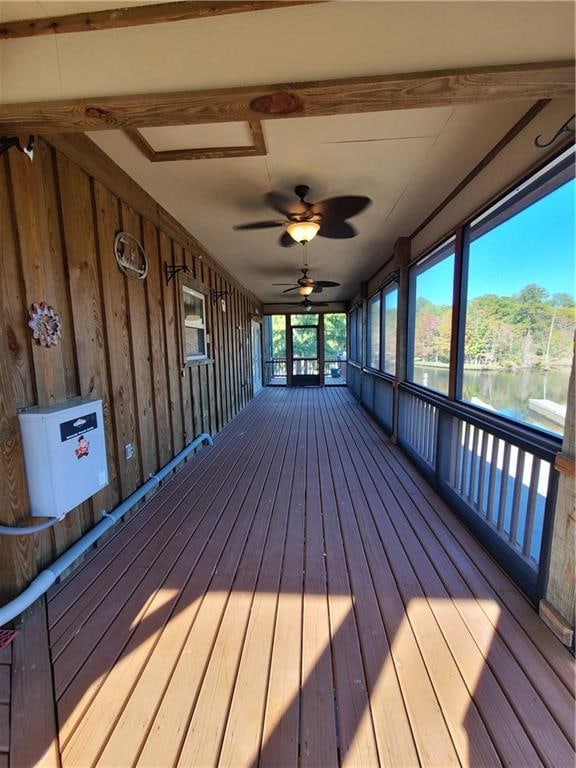 wooden deck with ceiling fan and a water view