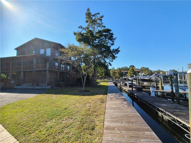 view of dock with a lawn and a water view