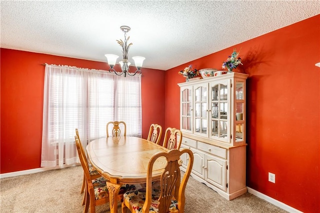 dining area featuring baseboards, a textured ceiling, light colored carpet, and a notable chandelier