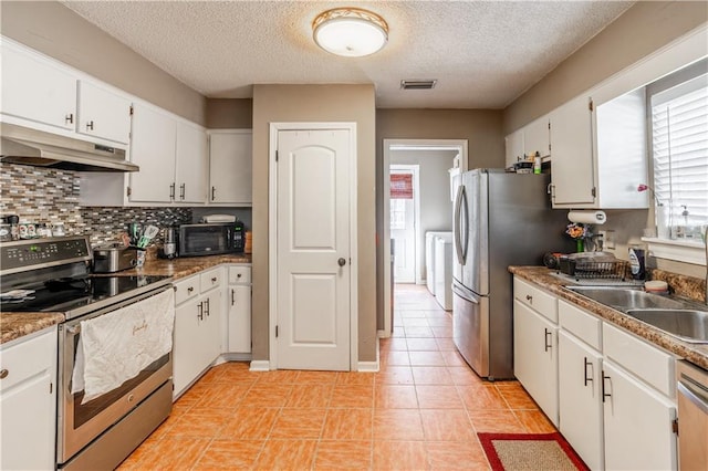 kitchen featuring under cabinet range hood, stainless steel appliances, a sink, visible vents, and backsplash