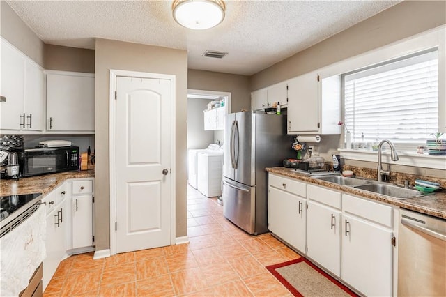 kitchen with washing machine and clothes dryer, visible vents, appliances with stainless steel finishes, white cabinets, and a sink