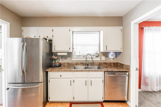 kitchen with stainless steel appliances, white cabinetry, a sink, and a textured ceiling