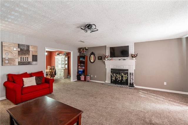 living room featuring a textured ceiling, baseboards, a fireplace with raised hearth, and carpet flooring