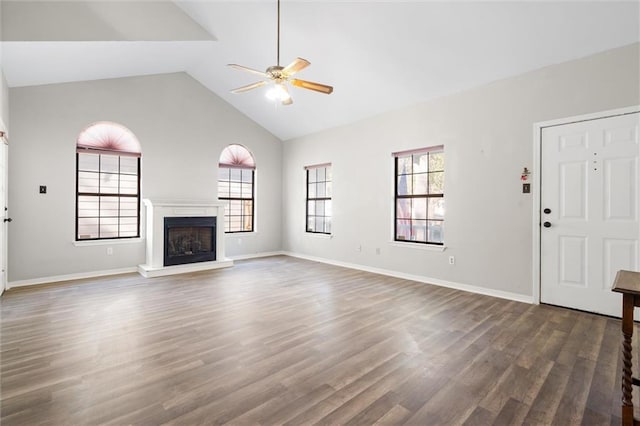 unfurnished living room featuring dark wood-type flooring, ceiling fan, plenty of natural light, and high vaulted ceiling