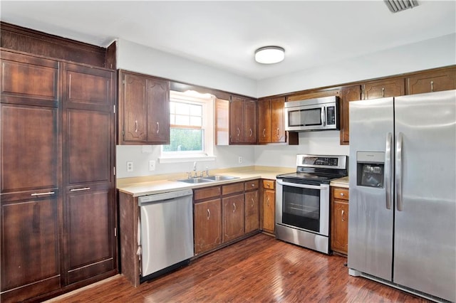 kitchen with stainless steel appliances, sink, and dark hardwood / wood-style flooring