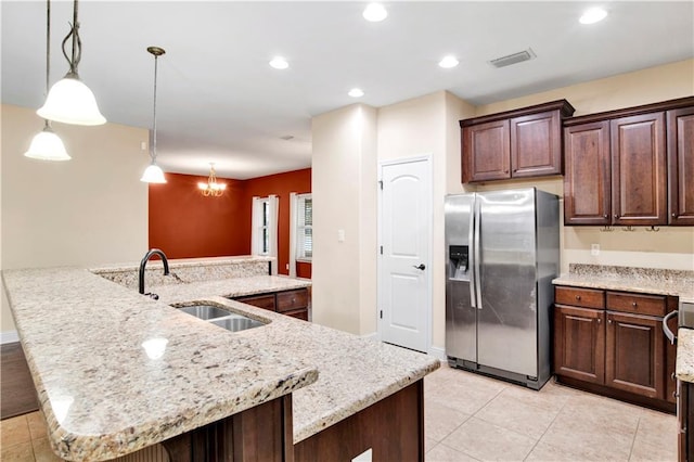 kitchen with stainless steel fridge, a spacious island, sink, pendant lighting, and a notable chandelier