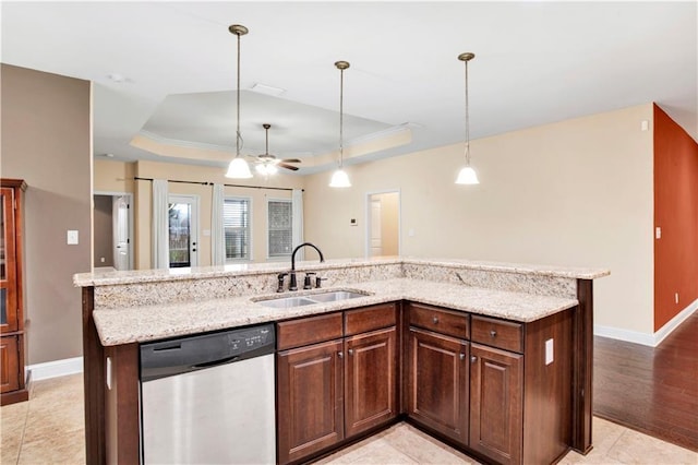 kitchen featuring stainless steel dishwasher, a tray ceiling, ceiling fan, sink, and an island with sink