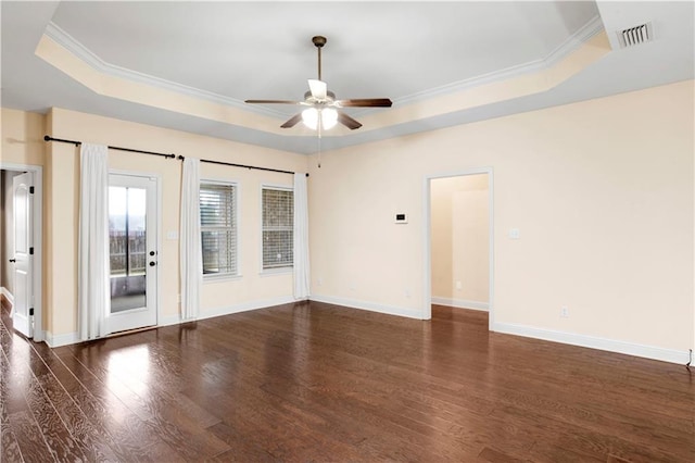 empty room with ornamental molding, a raised ceiling, and dark wood-type flooring