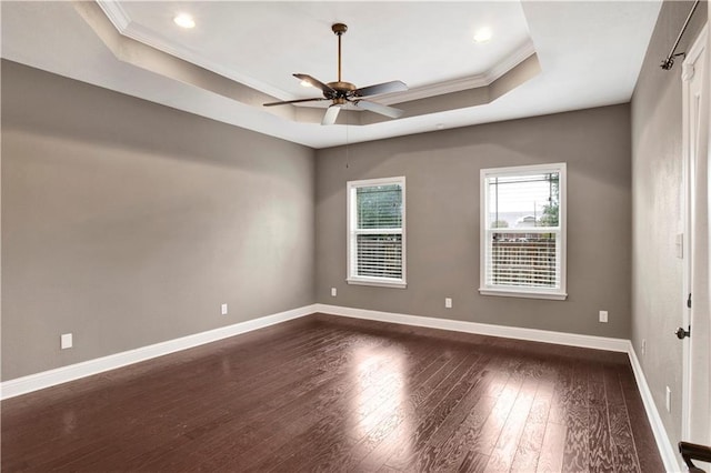 empty room featuring a tray ceiling, crown molding, dark hardwood / wood-style flooring, and ceiling fan