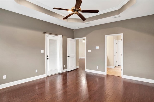 spare room featuring dark hardwood / wood-style floors, ceiling fan, a raised ceiling, and ornamental molding