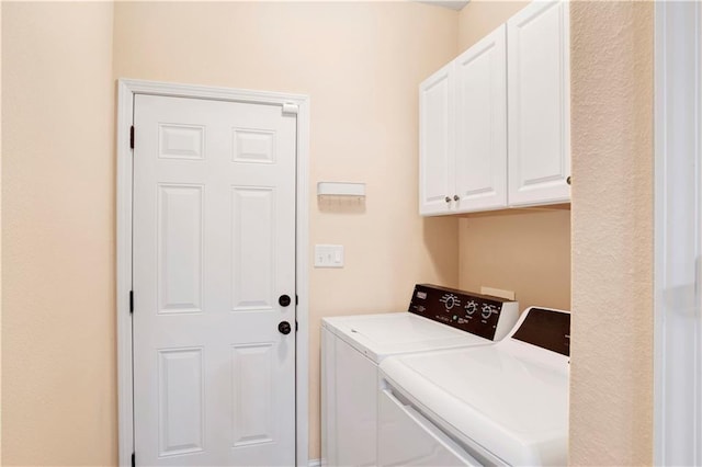 clothes washing area featuring washer and dryer and cabinets