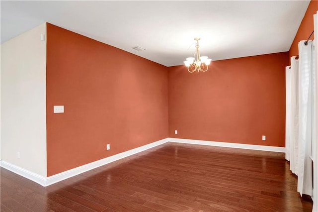 unfurnished room featuring dark hardwood / wood-style floors and an inviting chandelier