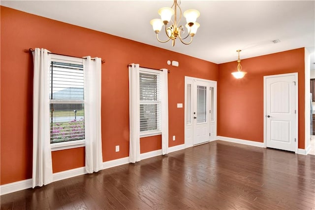 unfurnished room featuring dark hardwood / wood-style floors and a notable chandelier