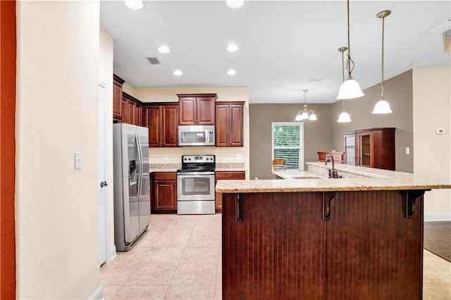 kitchen with stainless steel appliances, sink, decorative light fixtures, an inviting chandelier, and a breakfast bar area