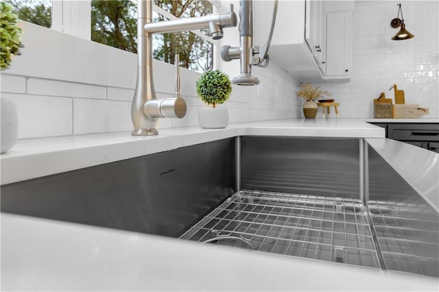 room details with tasteful backsplash, white cabinetry, and sink