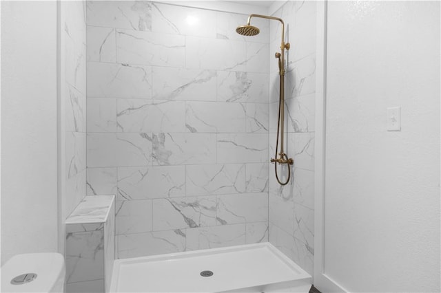 bathroom with a tile shower and toilet