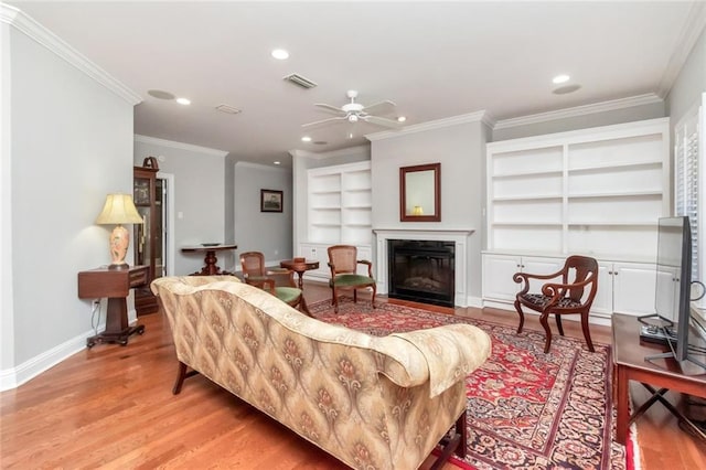 living area with baseboards, visible vents, a glass covered fireplace, light wood-style floors, and recessed lighting