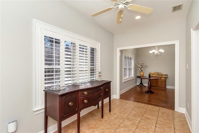 hall with light tile patterned floors, baseboards, visible vents, and a chandelier