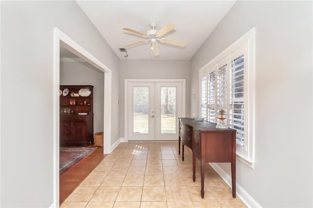 doorway featuring light tile patterned floors, baseboards, a ceiling fan, and french doors