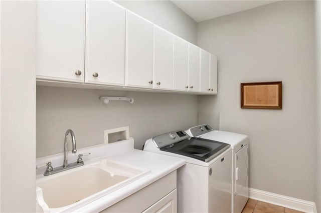 laundry room with light tile patterned floors, cabinet space, washing machine and dryer, a sink, and baseboards