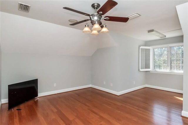 additional living space featuring ceiling fan, wood finished floors, visible vents, baseboards, and vaulted ceiling