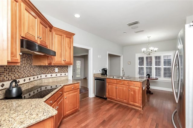 kitchen featuring stainless steel appliances, brown cabinetry, hanging light fixtures, and under cabinet range hood