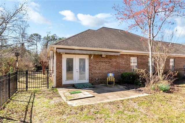 back of property with french doors, brick siding, a yard, a patio area, and fence