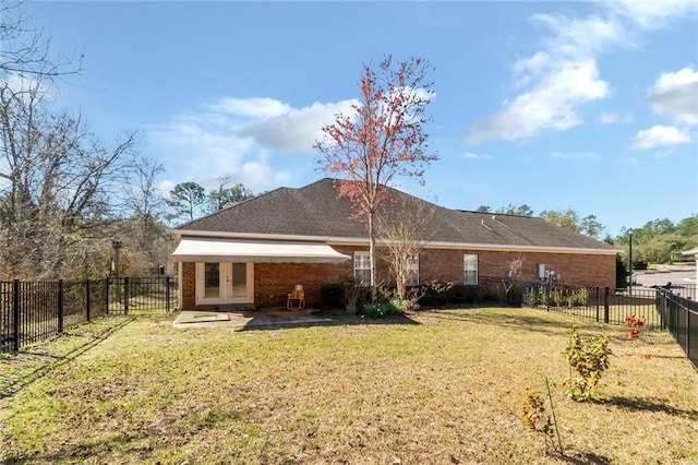 rear view of property featuring brick siding, a fenced backyard, and a yard